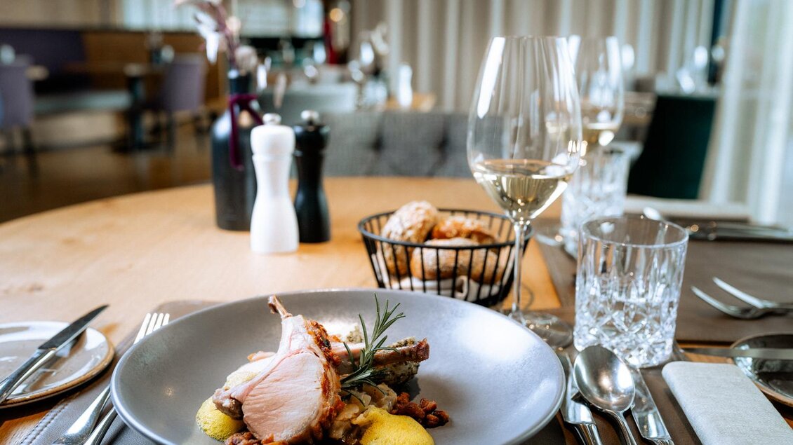 Ein stilvoll gedeckter Tisch mit einem exquisiten Gericht. Im Hintergrund sind Wein und weitere Delikatessen zu sehen. | © Daniel Obersberger