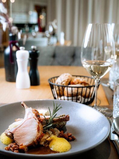 A stylishly set table with an exquisite dish. In the background, wine and other delicacies can be seen. | © Daniel Obersberger