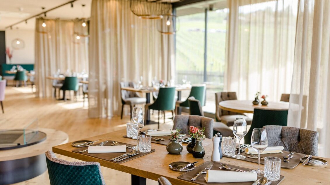 Ein elegantes Restaurant mit stilvollen Tischen und Stühlen. Große Fenster bieten einen Blick auf die grüne Landschaft. | © Karin Bergmann