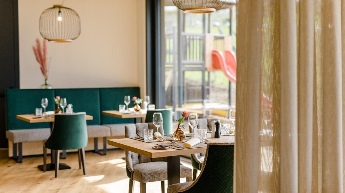 Ein stilvolles Restaurant mit modernen Tischen und Stühlen. Durch große Fenster fällt viel Licht und bietet einen Blick auf einen Außenbereich. | © Karin Bergmann