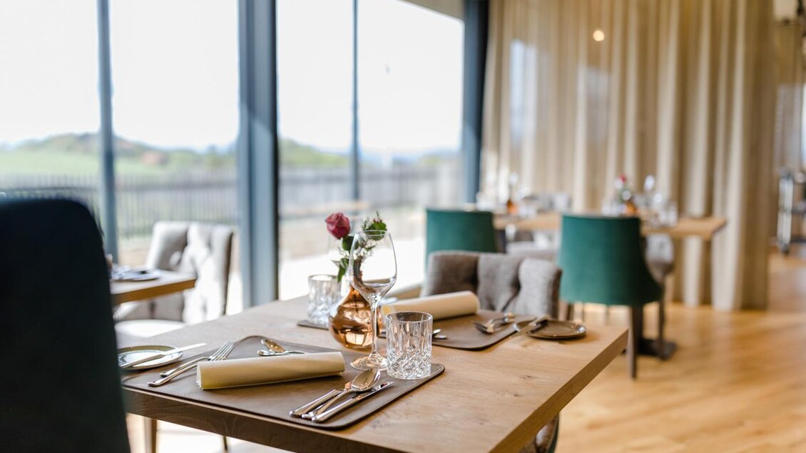 Ein elegantes Restaurant mit Holztischen und stilvollen Stühlen. Große Fenster bieten einen Blick ins Freie und viel Tageslicht mit Blick in den Weingarten. | © Karin Bergmann