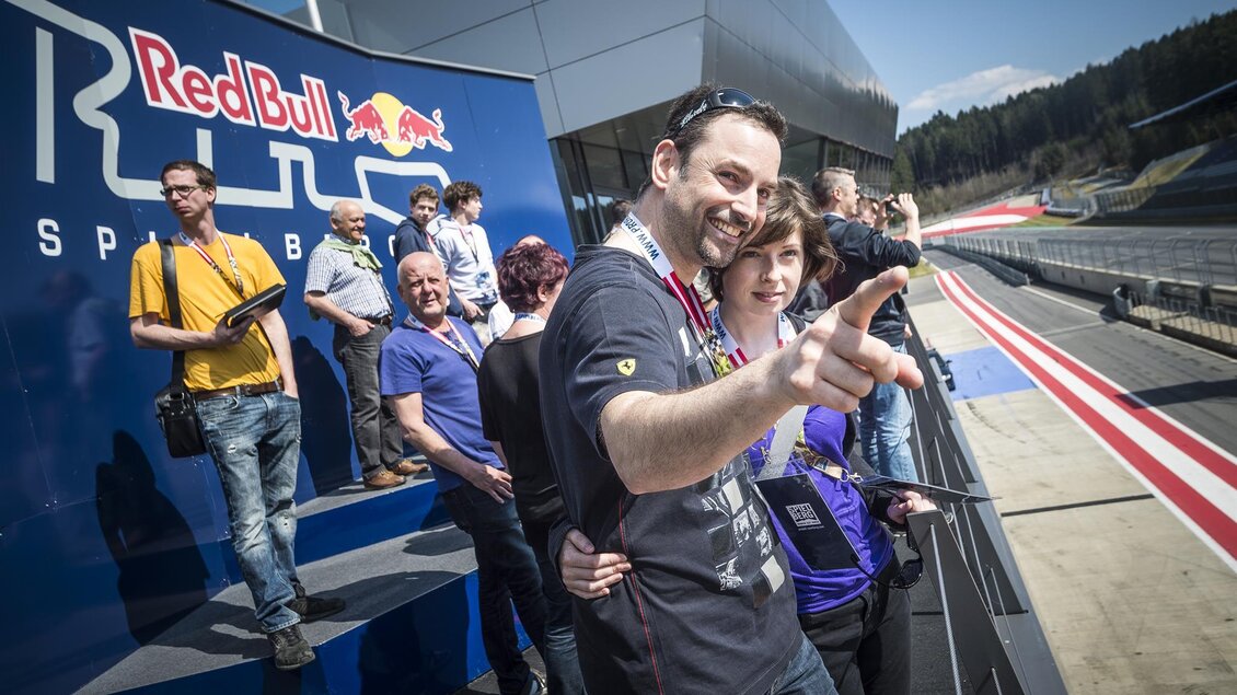 Eine Gruppe von Menschen steht auf einer Tribüne im Red Bull Ring. Sie lächeln und posieren für die Kamera an einem sonnigen Tag. | © Philip Platzer