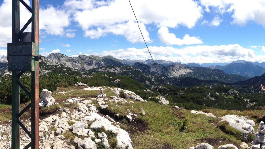 Ein atemberaubender Bergblick mit grünen Wiesen und felsigen Landschaften. Der Himmel ist blau mit einigen Wolken. | © Bettina Scheck