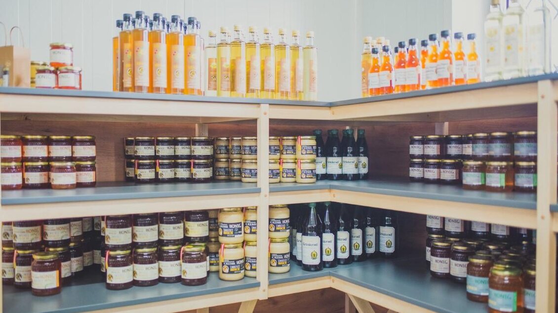 Ein Regal voller Flaschen und Gläser mit verschiedenen Lebensmitteln. Die Produkte umfassen Säfte, Marmeladen und Essig in bunten Verpackungen. | © RM SW GmbH | webquartier.at