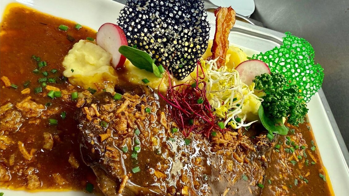 Ein schmackhaftes Stück Rindersteak in einer reichhaltigen Sauce, serviert mit Kartoffelpüree und buntem Gemüse. Die ansprechende Garnitur verleiht dem Gericht eine kreative Note. | © Gross Genuss GmbH