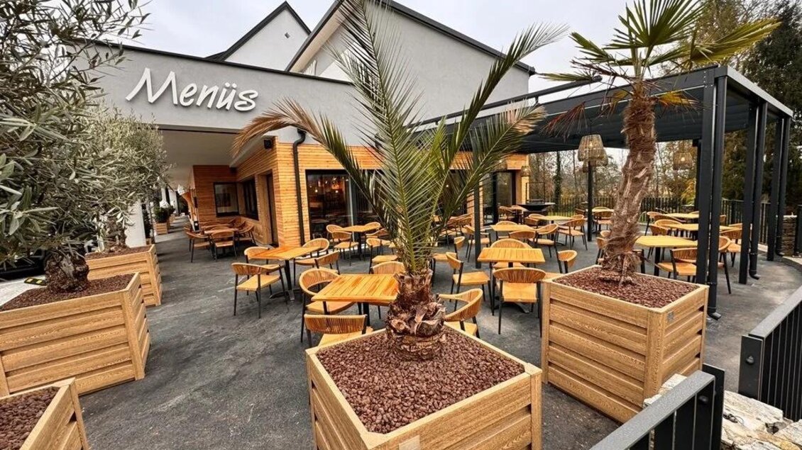 Ein modernes Restaurant mit einer einladenden Terrasse. Die Sitzbereiche sind von Pflanzen umgeben und bieten eine gemütliche Atmosphäre. | © Gross Genuss GmbH