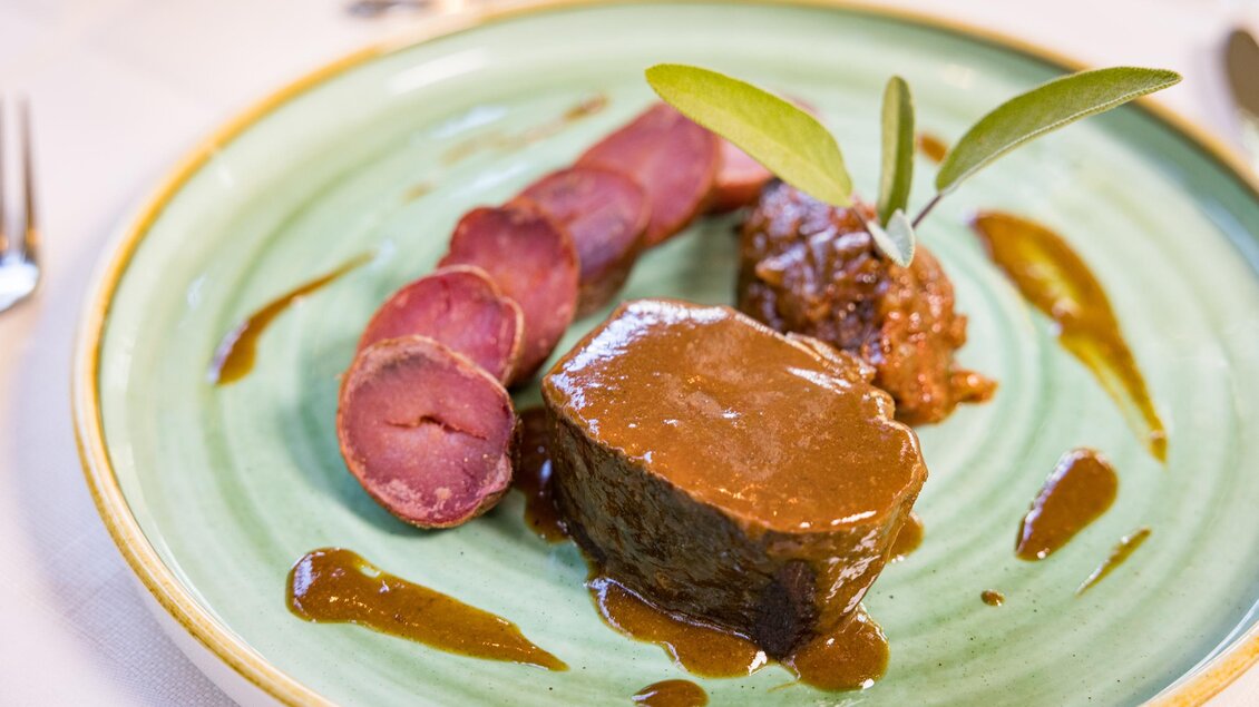 Ein delikates Gericht mit saftigem Fleisch, begleitet von einer würzigen Sauce. Beilagen bestehen aus dünn geschnittenem Fleisch und einer kleinen Portion einer herzhaften Beilage. | © Netzwerk Kulinarik wildbild