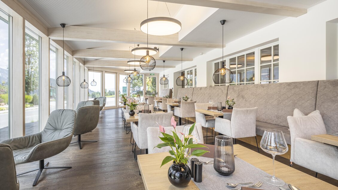 Ein modernes Restaurant mit großen Fenstern und einladenden Tischen. Die Einrichtung ist stilvoll und hell, mit Pflanzen und eleganter Beleuchtung. | © vison