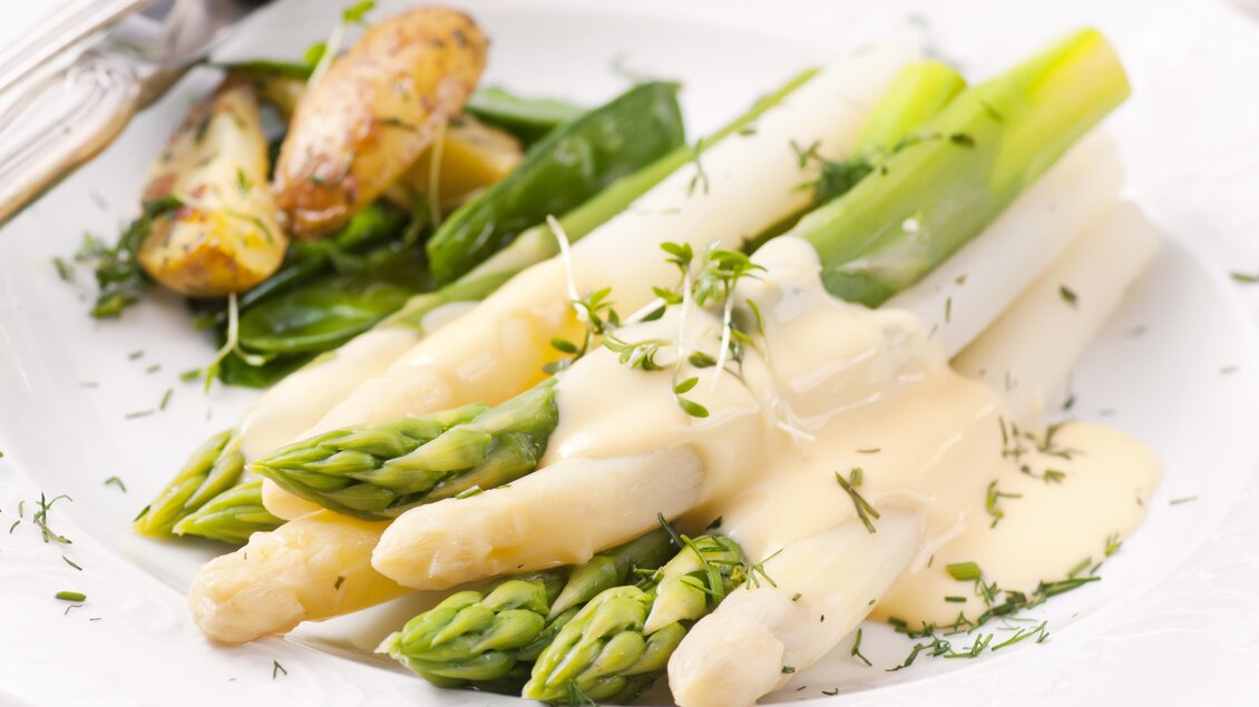 Ein Teller mit frischem Spargel, begleitet von Kartoffeln und grünem Gemüse. Die Speise ist mit einer cremigen Sauce und frischen Kräutern garniert. | © Hotel Böhlerstern