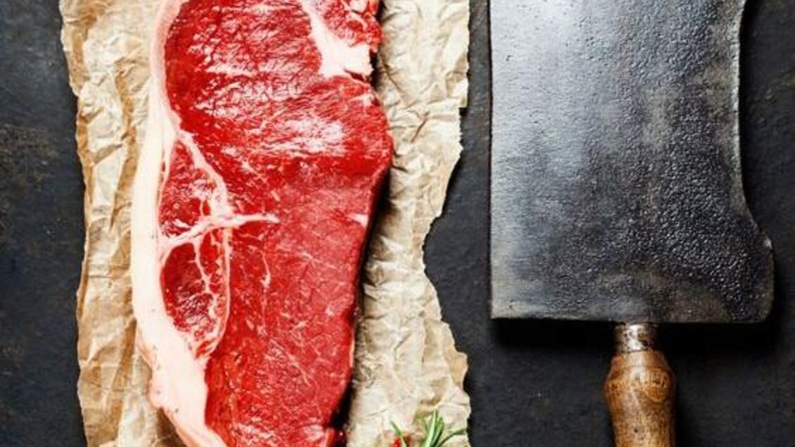 Ein frisches Stück Fleisch auf braunem Papier, umgeben von Knoblauch, Kartoffeln und Kräutern. Ein Fleischmesser liegt daneben, und es sind Gewürze sowie Olivenöl sichtbar. | © Hotel Böhlerstern