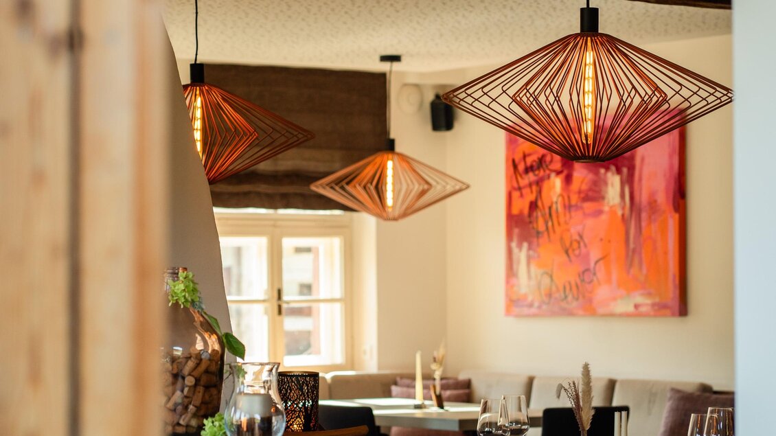 Ein modernes Restaurant mit stilvollen Lampen und einer bunten Wandkunst. Der Raum ist einladend und freundlich gestaltet. | © Koch Julia