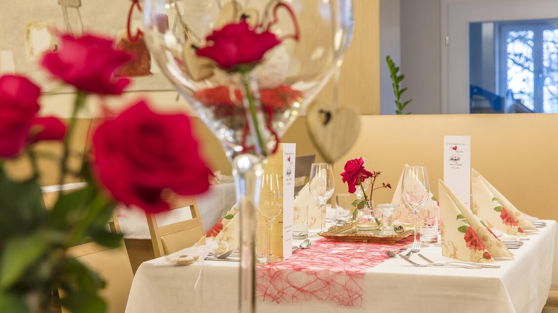 Ein elegant gedeckter Tisch mit roten Rosen und schönem Geschirr. Die Atmosphäre ist festlich und einladend. | © Gollner