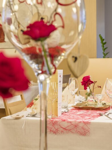 Ein elegant gedeckter Tisch mit roten Rosen und schönem Geschirr. Die Atmosphäre ist festlich und einladend. | © Gollner