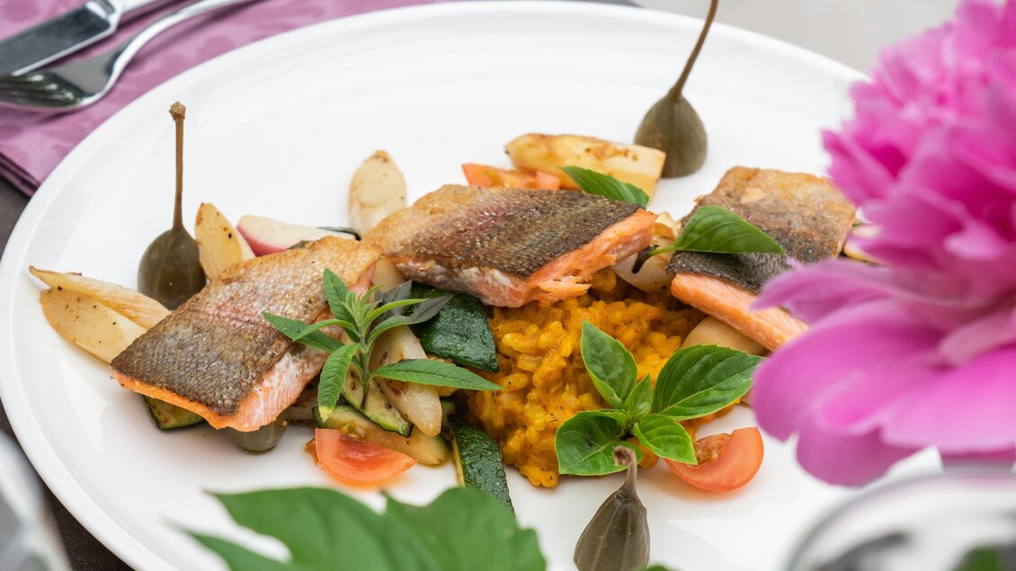 Ein kunstvoll angerichteter Teller mit gebratenem Fisch, Gemüse und einer würzigen Beilage. Frische Kräuter und kleine Beilagen sorgen für eine ansprechende Präsentation. | © Gollner