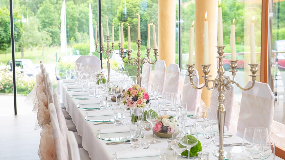 Ein elegant gedeckter Tisch mit Kerzenleuchtern und Blumenarrangements. Die Atmosphäre ist festlich und einladend. | © Helmut Schweighofer