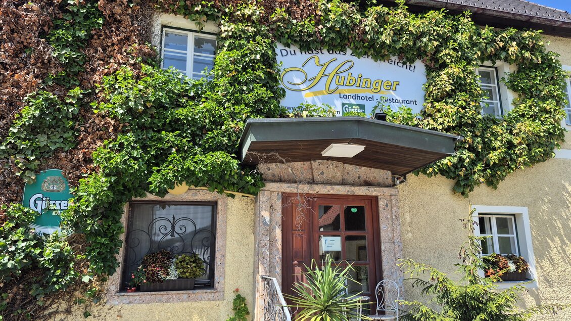 Ein charmantes Gasthaus mit einer begrünten Fassade und einem einladenden Eingang. Über der Tür prangt das Schild mit dem Namen "Hübinger". | © TV Hochsteiermark