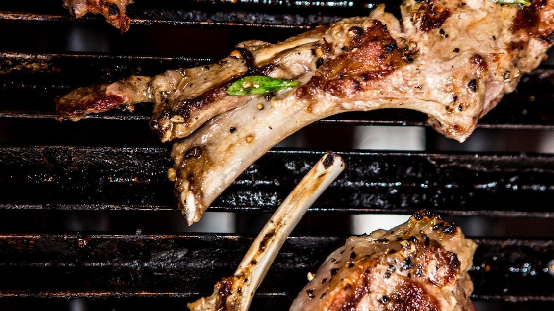 Gegrillte Lammkoteletts auf einem heißen Grill. Die Koteletts sind perfekt gebräunt und mit Kräutern garniert.