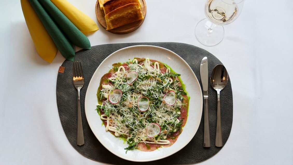 Ein Teller Pasta mit frischem Gemüse und Käse. Daneben ein Glas Wein und ein Stück Brot. | © Kirchenwirt Stubenberg