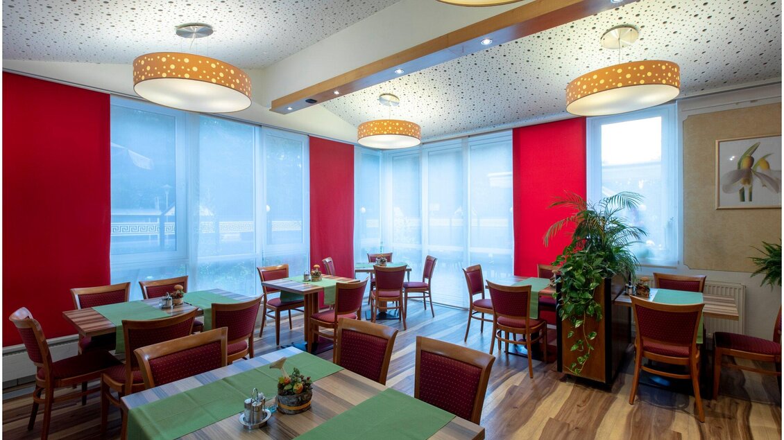 Ein helles Restaurant mit roten Wänden und gemütlichen Tischen. Die großen Fenster lassen viel Licht hinein und sorgen für eine einladende Atmosphäre. | © Region Graz - Lunghammer
