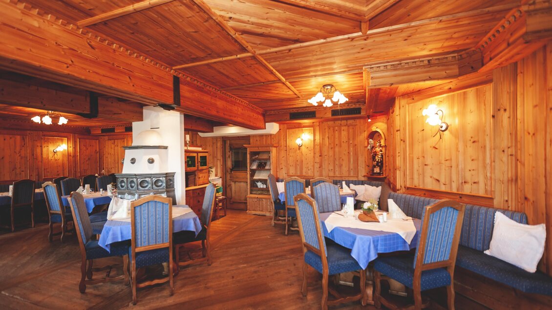 Ein gemütliches Restaurant mit Holzwänden und blauen Tischdecken. Die Tische sind für Gäste gedeckt und die Atmosphäre ist einladend. | © Karoline Karner