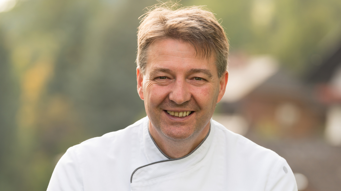Der Chefkoch Alfred Schwaiger vom Restaurant Schwaiger in Tauplitz lächelt in die Kamera. Im Hintergrund ist eine ländliche Umgebung zu sehen.</p></p> | © Restaurant Schwaiger