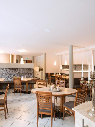 A modern restaurant with wooden tables and chairs. The walls are light and the lighting is warm and inviting. | © Sporthotel Kapfenberg