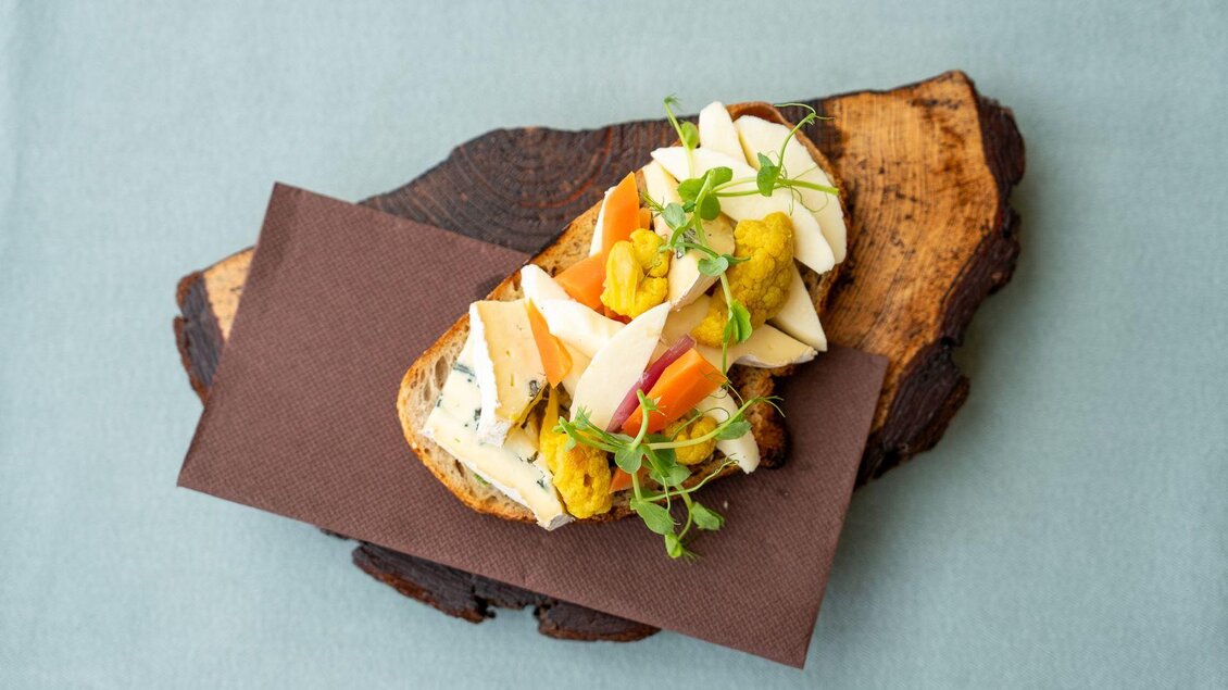 <p>A gute Jause verschiedenen Gemüse- und Käsesorten, dekoriert mit frischen Kräutern. Es liegt auf einem Holzbrett und ist ansprechend angerichtet.</p> | © Hotel Alpen Arnika
