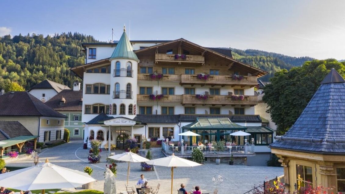 Traditionelles Hotel mit alpiner Architektur, großzügiger Terrasse und gemütlichem Gartenbereich vor Bergkulisse. | © Hotel Herrschaftstaverne