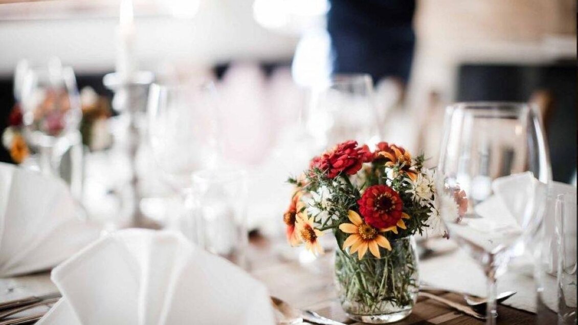 Ein schön gedeckter Tisch mit eleganten Gläsern und einem bunten Blumenstrauß. Die Tischdekoration ist ansprechend und gemütlich. | © Hotel Herrschaftstaverne