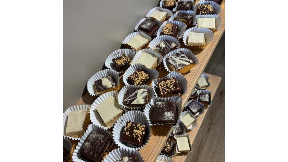 Eine Auswahl an süßen Leckereien in bunten Papierförmchen. Die Pralinen und Kuchen sind mit Schokolade und verschiedenen Toppings verziert. | © JUFA Hotel Leibnitz