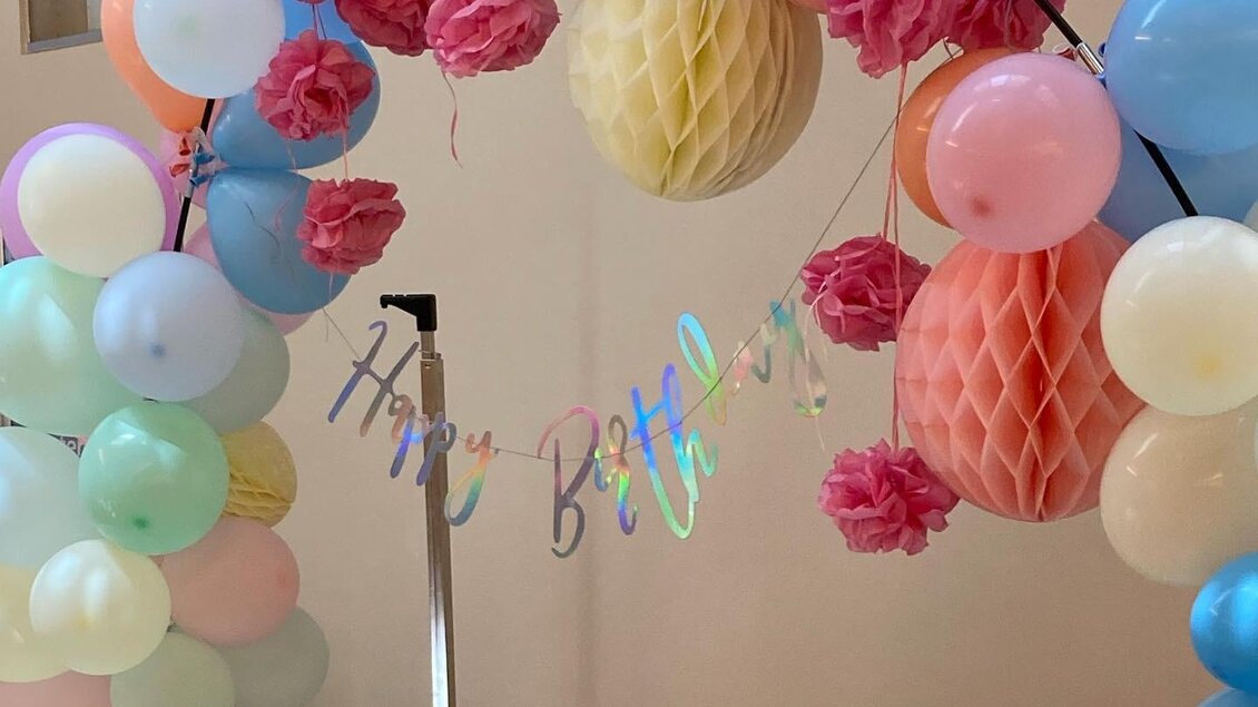 Ein festlicher Bogen aus bunten Ballons und Papierdekorationen schmückt einen Tisch für eine Geburtstagsfeier. Im Hintergrund hängt ein "Happy Birthday"-Schild. | © JUFA Hotel Leibnitz