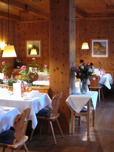 A couple toasts at a table outdoors in front of a restaurant. The surroundings are green and inviting, with a view of a hotel building in the background. | © SPA Hotel Erzherzog Johann, Bad Aussee, Restaurant (c) Ralf Tornow