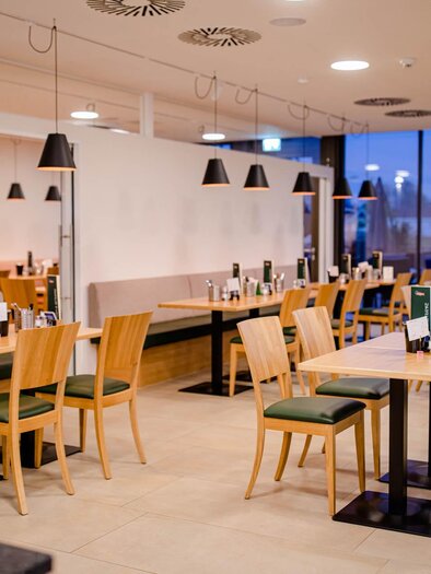 Ein modernes Restaurant mit hellen Tischen und Stühlen. Die Atmosphäre ist einladend und gemütlich mit sanfter Beleuchtung. | © F. Krainer Fleisch- & Wurstwaren GesmbH