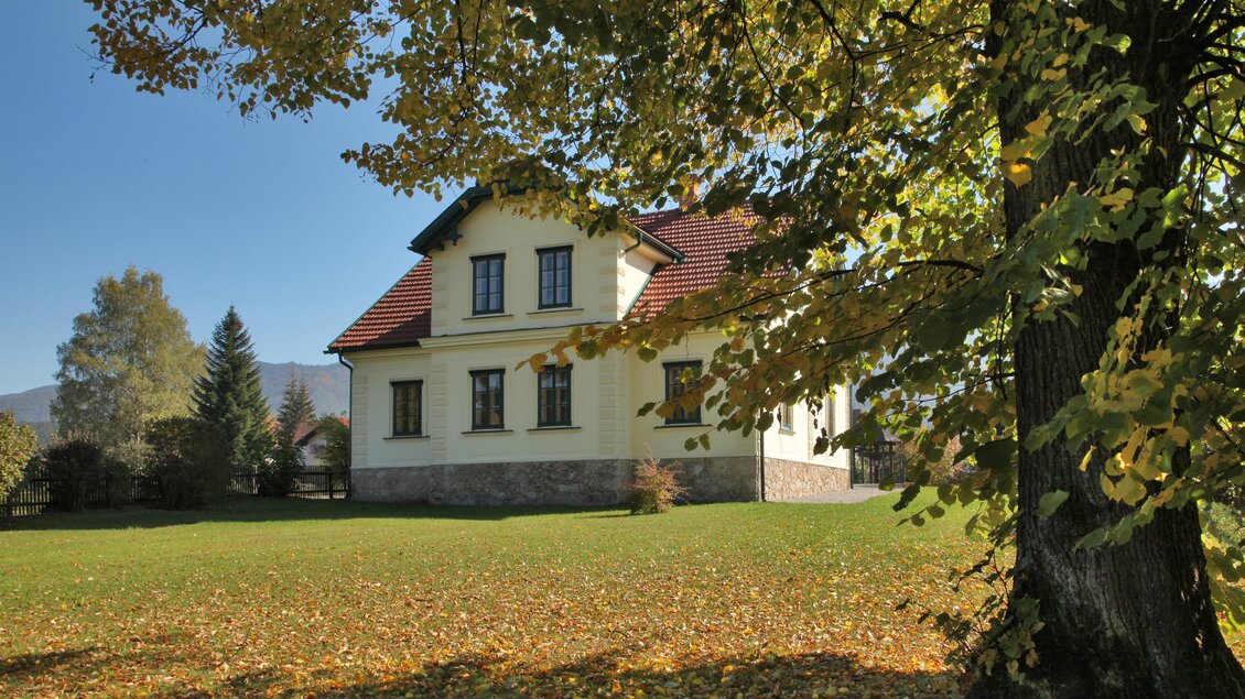 Ein charmantes Haus umgeben von buntem Herbstlaub. Der klare Himmel und die grüne Wiese verleihen der Szene eine einladende Atmosphäre. | © Jakob Hiller