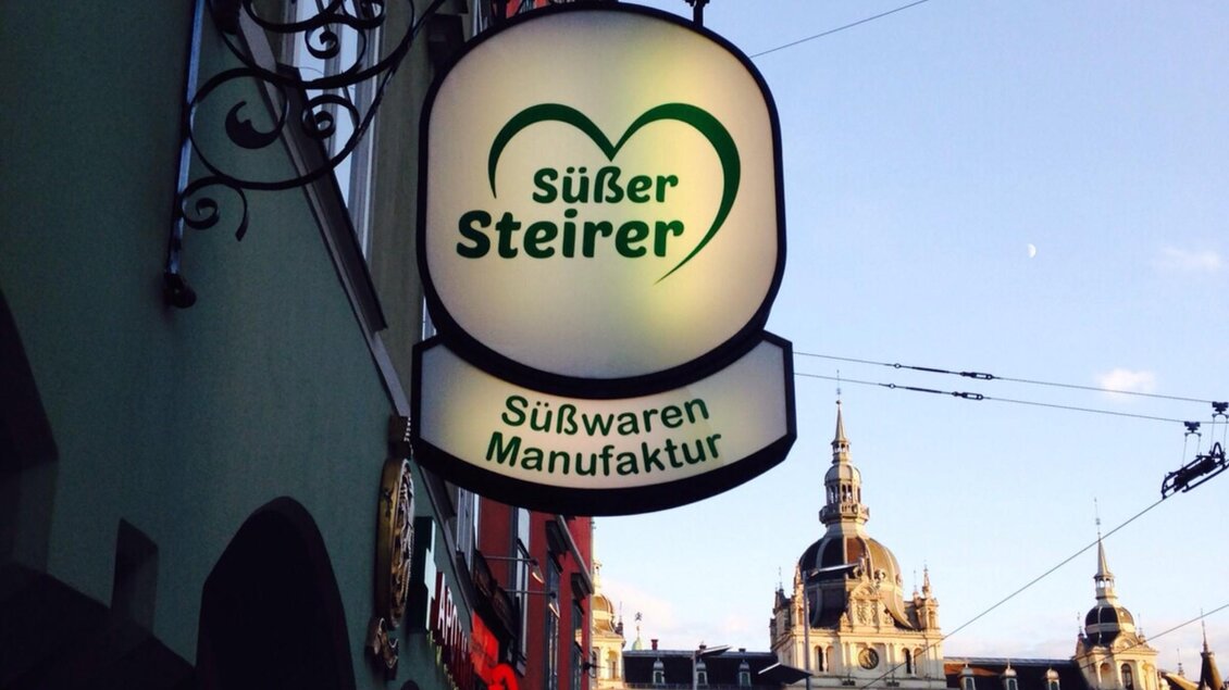 Geschäftsschild der Süßwarenmanufaktur „Süßer Steirer“ in der Grazer Innenstadt mit Blick auf das Rathaus. | © Süßer Steirer