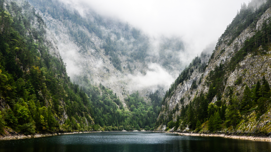 <p>Der ruhige Salza-Stausee umgeben von hohen Bergen und dichten Wäldern in Bad Mitterndorf. Der Himmel ist bewölkt, was eine mystische Stimmung schafft.</p> | © TVB Ausseerland Salzkammergut_Jaqueline Korber
