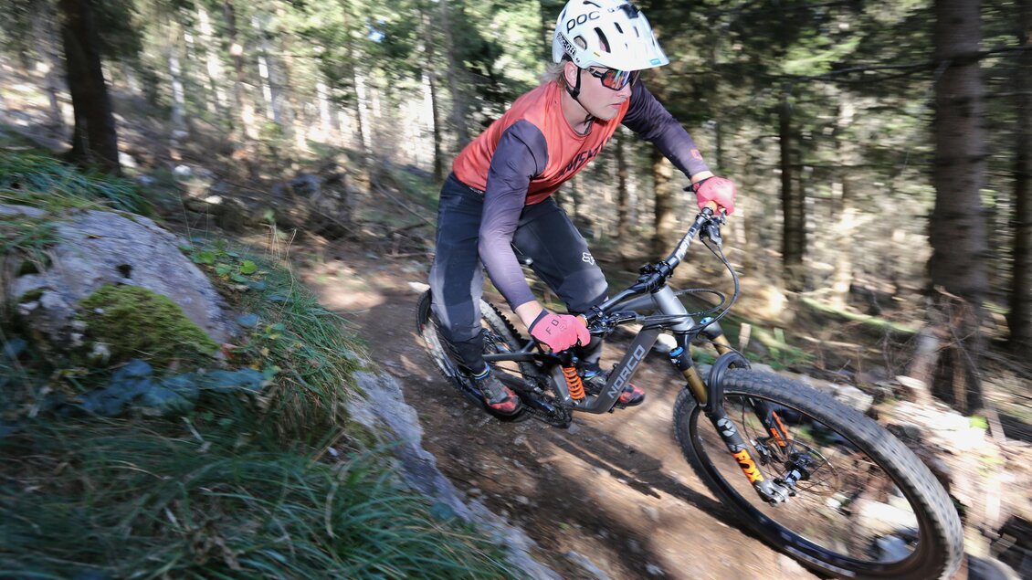 Mountainbiker mit Helm fährt auf einem schmalen, steinigen Schöckl Trail durch den Wald bergab. | © The Gap MTBing