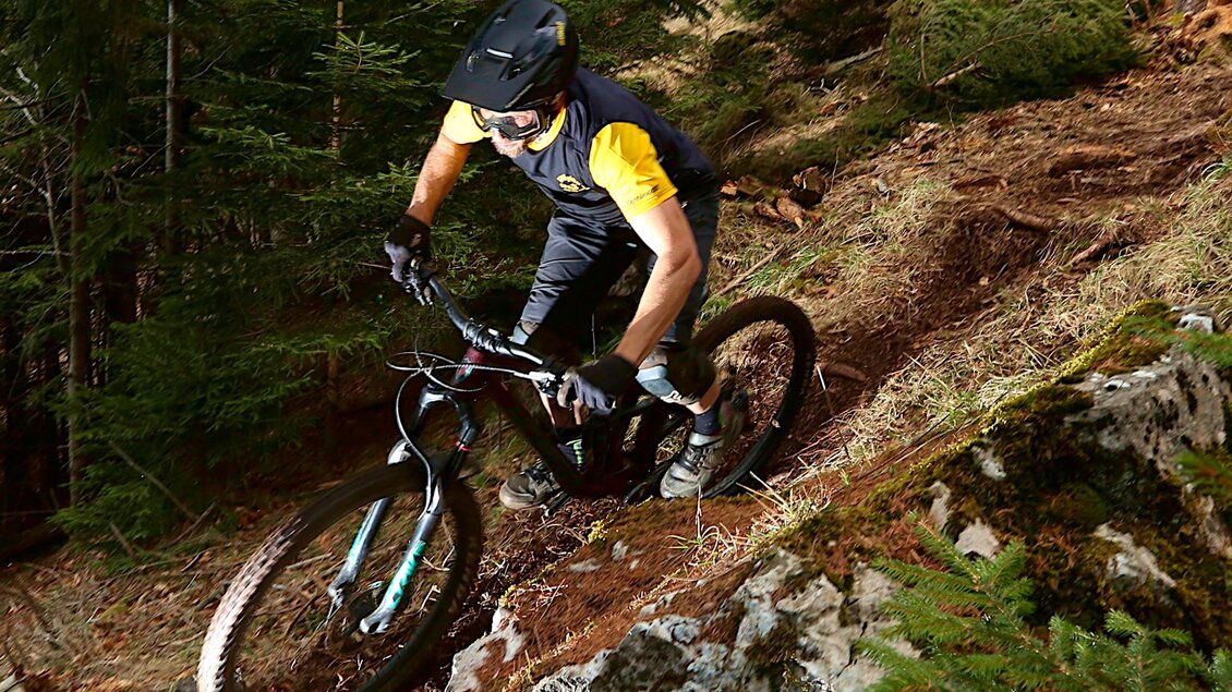 Mountainbiker mit Helm fährt auf einem schmalen, felsigen Trail durch den Wald am Schöckl bergab. | © The Gap MTBing