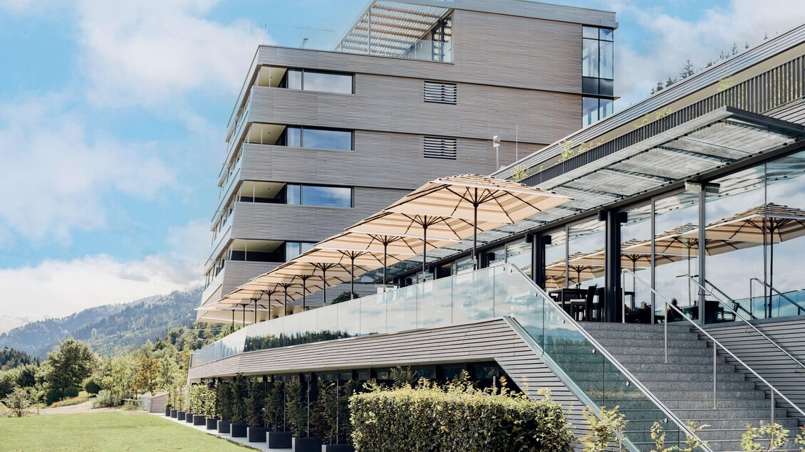 Ein modernes Gebäude mit großen Fenstern und Terrassen. Umgeben von einer grünen Landschaft und unter einem klaren Himmel. | © Tauroa GmbH