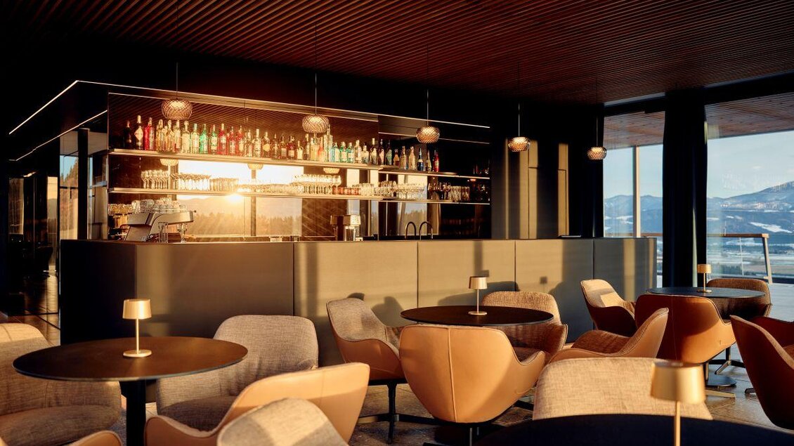 Eine moderne Bar mit eleganten Möbeln und einer stilvollen Atmosphäre. Große Fenster bieten einen schönen Blick auf die Landschaft. | © Tauroa GmbH