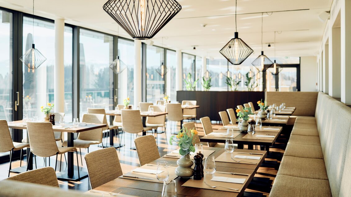 Ein modernes Restaurant mit großen Fenstern und eleganten Lampen. Die Tische sind schön gedeckt und bieten eine einladende Atmosphäre. | © Tauroa GmbH