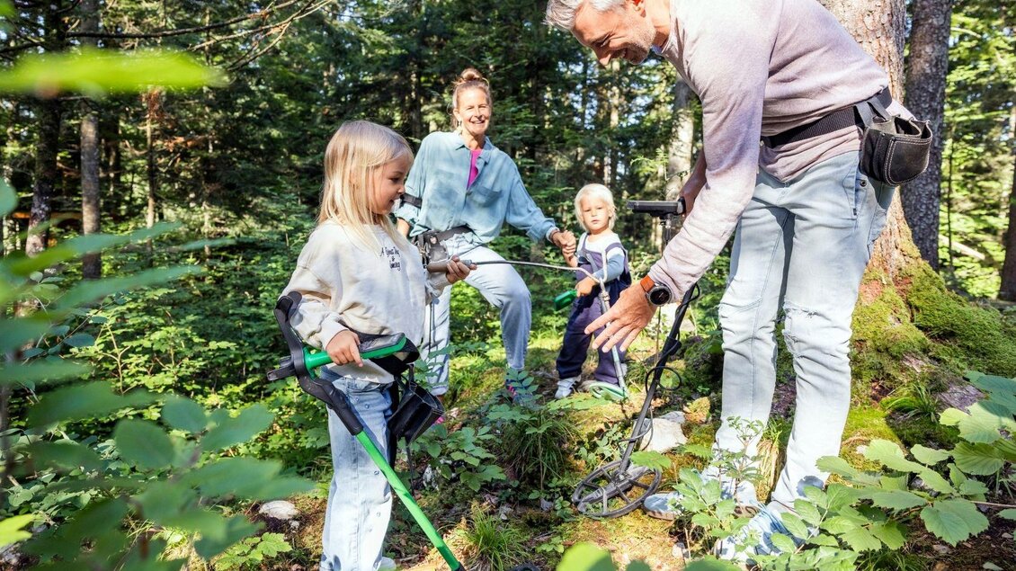 Eine Familie entdeckt den Wald mit einem Metalldetektor. Die Kinder sind neugierig und erforschen die Umgebung. | © www.zloam.at