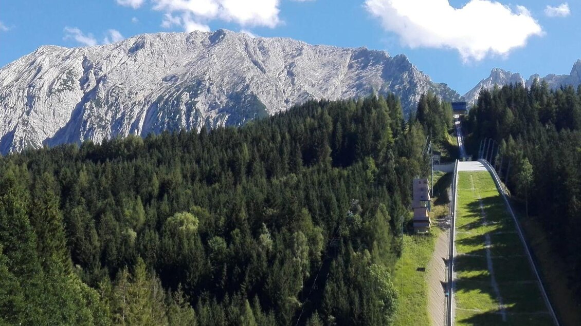 <p>Der malerisches Hausberg von Bad Mitterndorf der Grimming mit schneebedeckten Gipfeln und dichten Wäldern. Im Vordergrund ist eine Skiflugschanze der Kulm zu sehen, die sich durch die Landschaft zieht.</p> | © TVB Ausseerland Salzkammergut/Raunigg