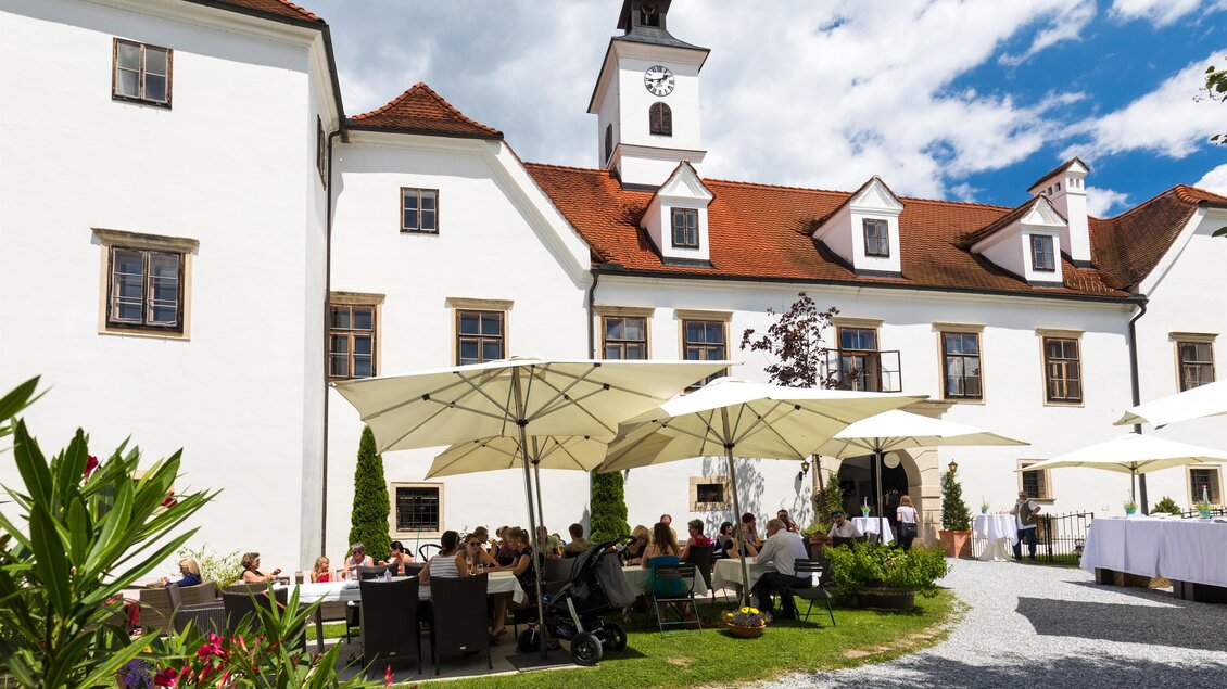 Innenhof von Schloss Dornhofen in Eggersdorf bei Graz mit Gästen unter Sonnenschirmen und Turm am Schlossdach. | © Region Graz-Harry Schiffer