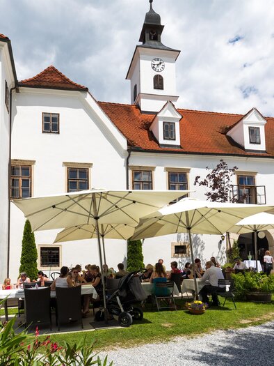 Innenhof von Schloss Dornhofen in Eggersdorf bei Graz mit Gästen unter Sonnenschirmen und Turm am Schlossdach. | © Region Graz-Harry Schiffer