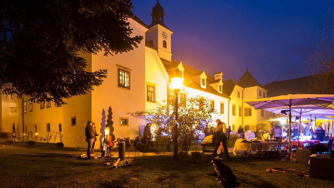 Schloss Dornhofen in Eggersdorf bei Graz bei Nacht mit beleuchteter Fassade, Gästen im Garten und Feier unter Schirmen. | © Region Graz-Harry Schiffer