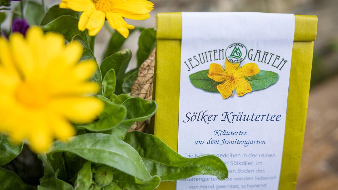 Ein Kräutertee aus dem Jesuitengarten in einer hübschen Verpackung. Im Vordergrund sind gelbe Blumen zu sehen. | © wildbild