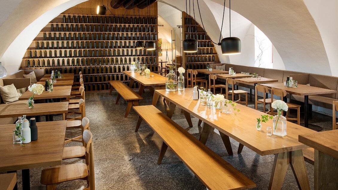 Ein modernes Restaurant mit hellen Holztischen und Bänken. Die Wände sind mit einer stilvollen Regalreihe dekoriert. | © Stefan Kristoferitsch