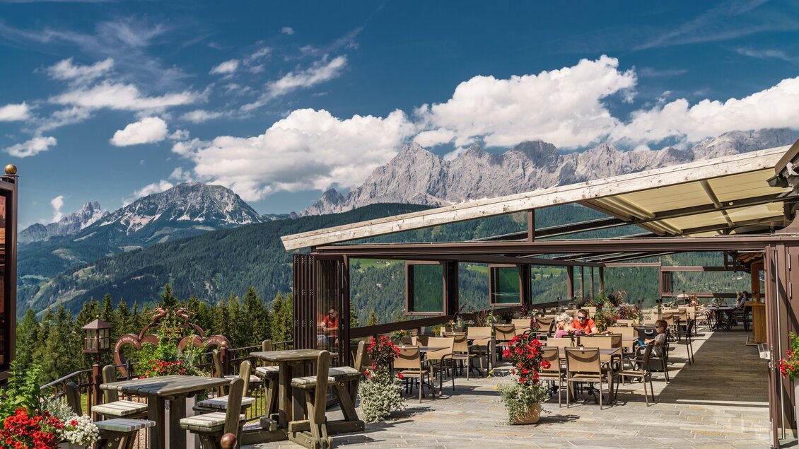 Ein schönes Restaurant mit Terrasse in den Bergen. Im Hintergrund sind beeindruckende Gipfel und ein blauer Himmel zu sehen. | © Christine Höflehner
