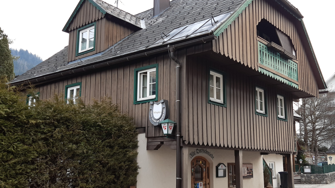 Ein traditionelles Holzhaus mit einem breiten Dach und grünen Fensterrahmen. Vor dem Haus befindet sich eine kleine Hecke und ein Schild mit dem Namen des Hauses. | © TVB Ausseerland Salzkammergut_Daniela Casari